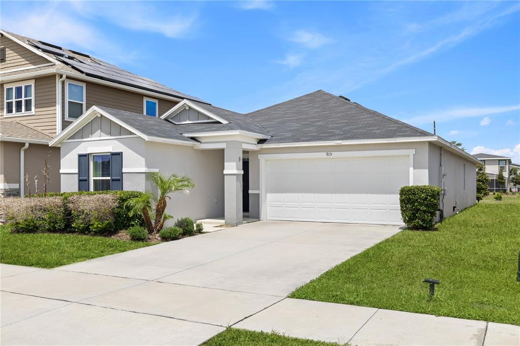 A kitchen features white cabinets, granite countertops, a center island with seating, and wood flooring — 915 OVERPOOL AVENUE, DAVENPORT, FL