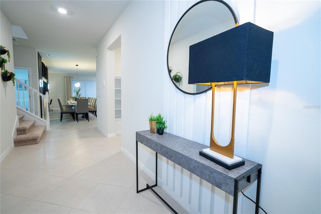 A modern entryway features a gray console table, a gold lamp, and a round mirror — 16276 SAINT MARTIN STREET, CLERMONT, FL