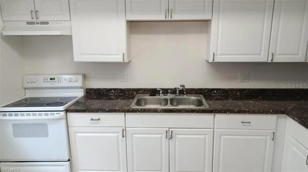 A kitchen features white cabinets, a dark brown countertop, and a white electric range — 2524 CONGRESS STREET UNIT #4, FORT MYERS, FL