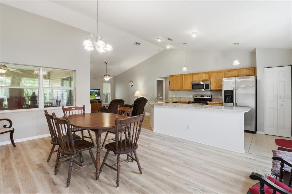An open-concept kitchen and dining area features light wood flooring, oak cabinets, and stainless appliances — 9735 W DUNNELLON ROAD, CRYSTAL RIVER, FL