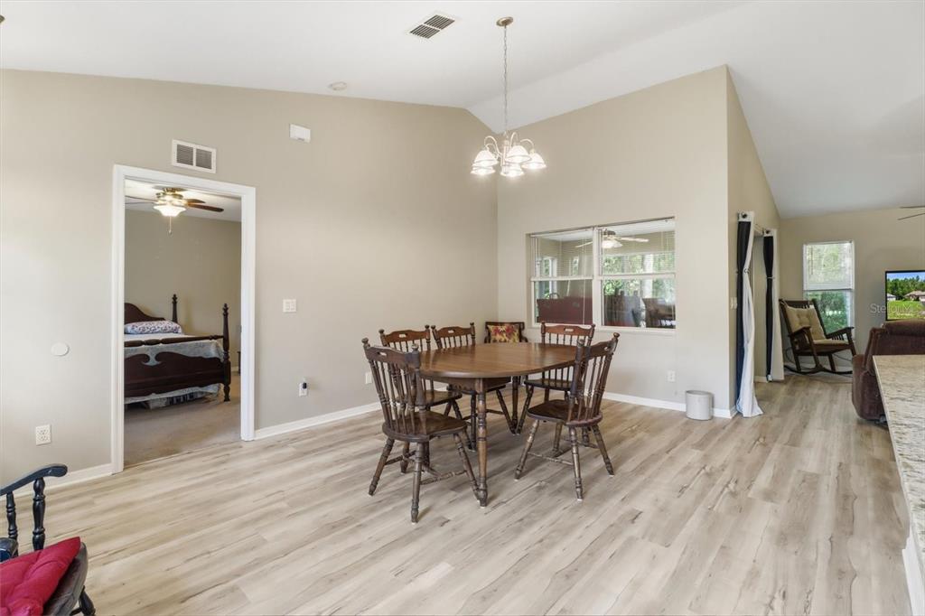 A dining area with a wooden table and chairs sits under a vaulted ceiling — 9735 W DUNNELLON ROAD, CRYSTAL RIVER, FL