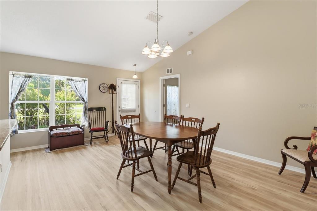 A dining room features a wooden table, chairs, light wood flooring, and a vaulted ceiling — 9735 W DUNNELLON ROAD, CRYSTAL RIVER, FL