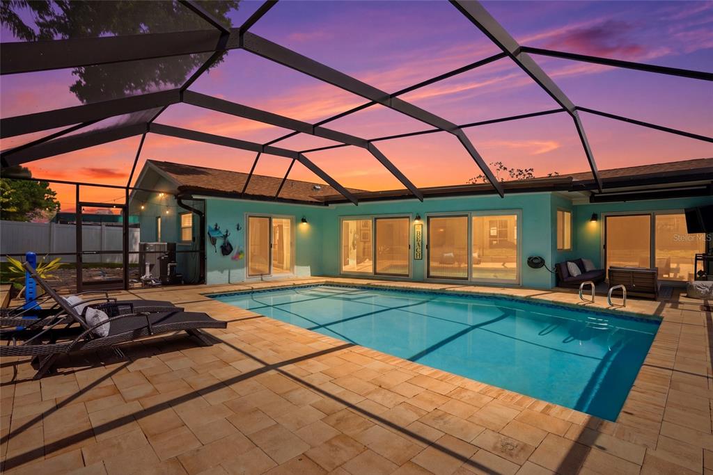 A swimming pool with a screened enclosure sits on a patio outside a house — 2089 SWAN LANE, SAFETY HARBOR, FL