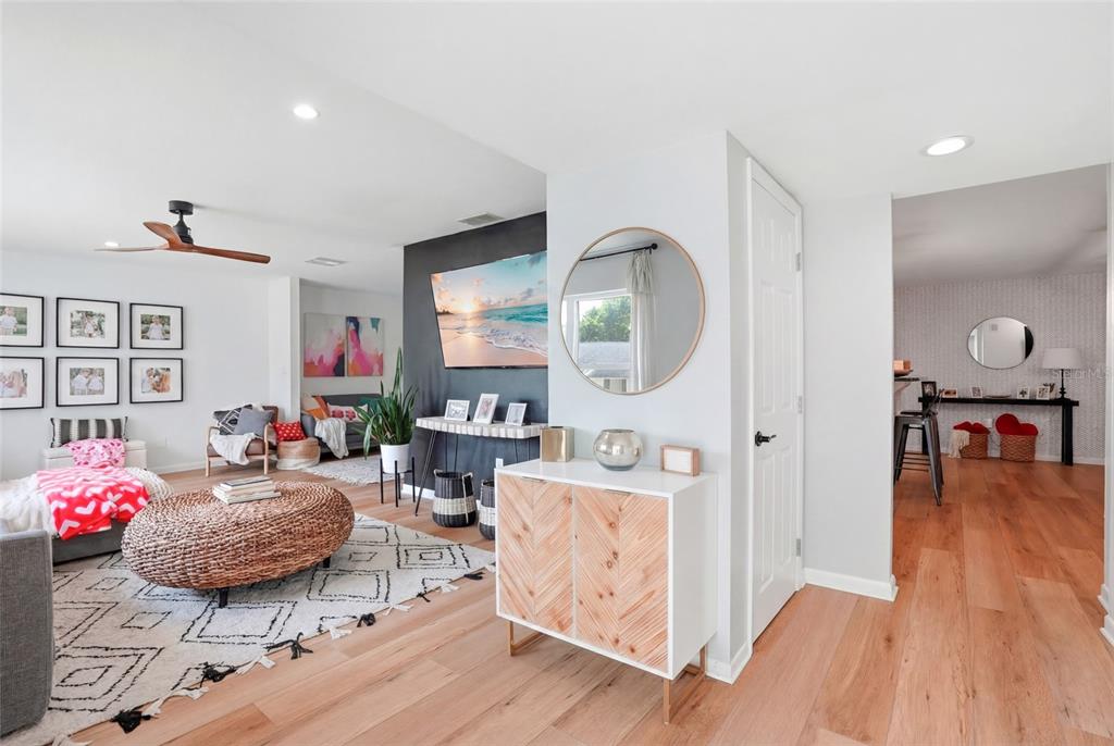 A living room features a round woven ottoman, a dark accent wall, and wood flooring — 2089 SWAN LANE, SAFETY HARBOR, FL