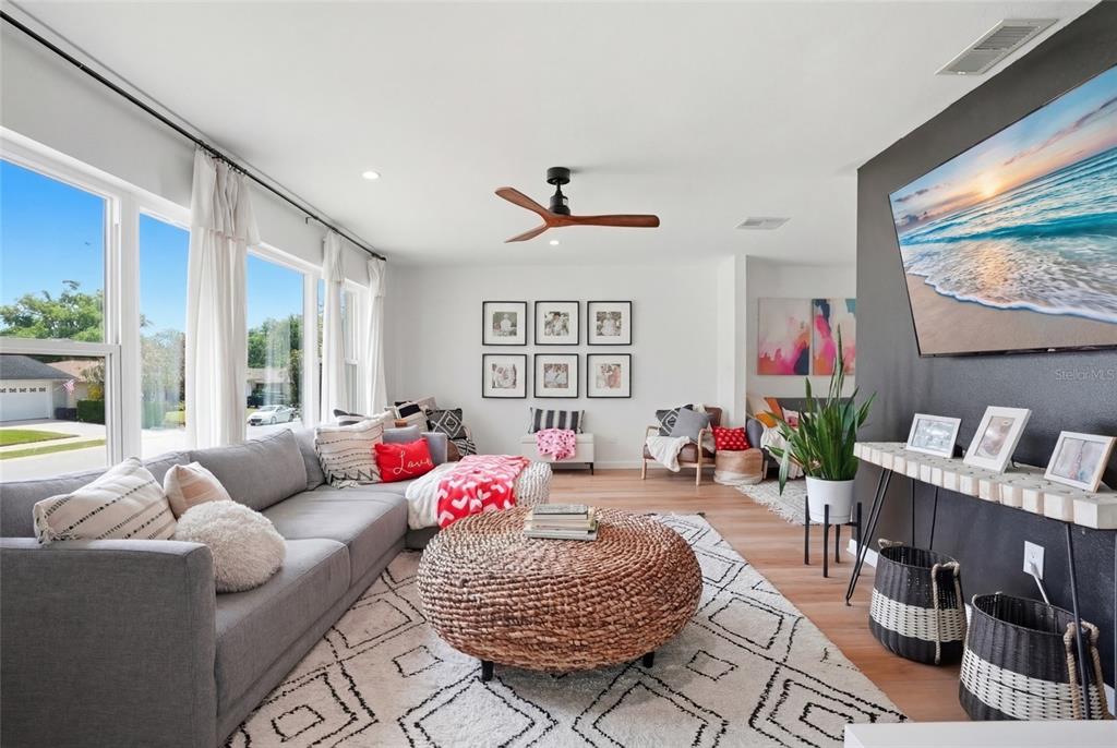 A living room features a gray sectional sofa, a round woven ottoman, and a wall-mounted television — 2089 SWAN LANE, SAFETY HARBOR, FL
