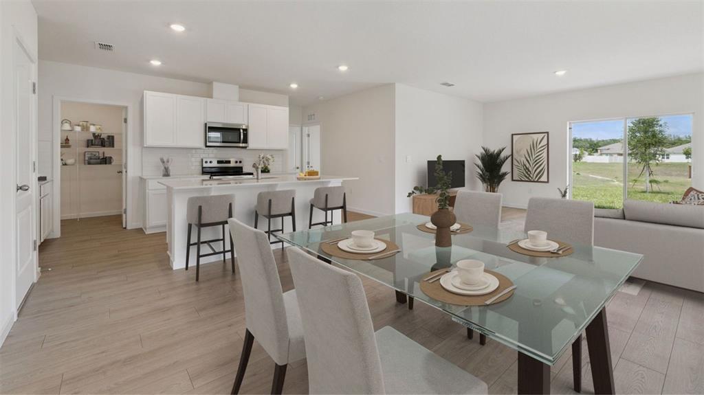 An open-concept kitchen and dining area features white cabinets, a glass table, and light flooring — 1376 GRAND FLORA LANE, SANFORD, FL