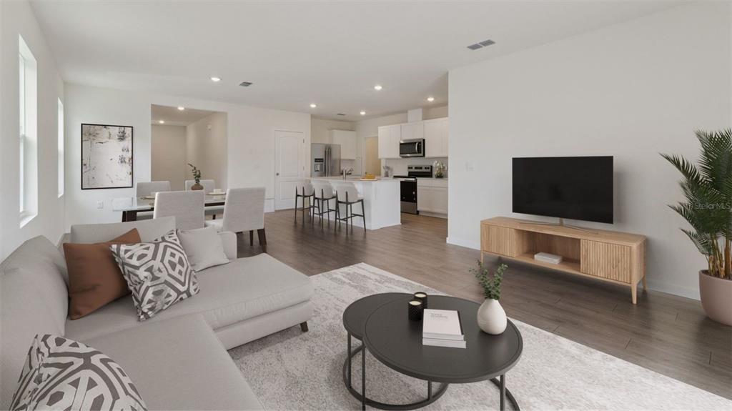 This open-concept living area features a kitchen with an island, dining space, and neutral decor — 1376 GRAND FLORA LANE, SANFORD, FL