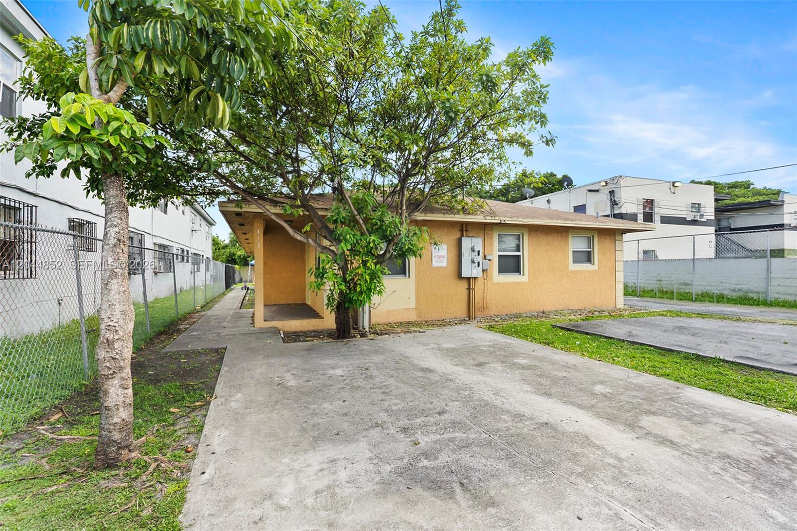 A single-story tan house with a concrete driveway and a large tree in the front — 812 NW 70th St, Miami FL 33150, MIAMI, FL
