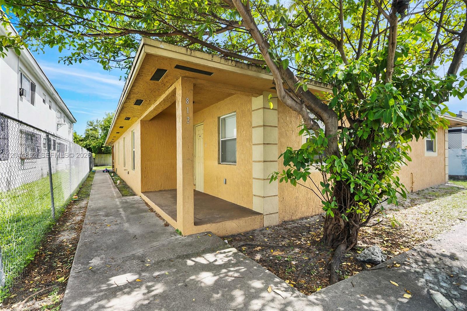 A yellow single-story house with a covered porch and a concrete walkway — 812 NW 70th St, Miami FL 33150, MIAMI, FL