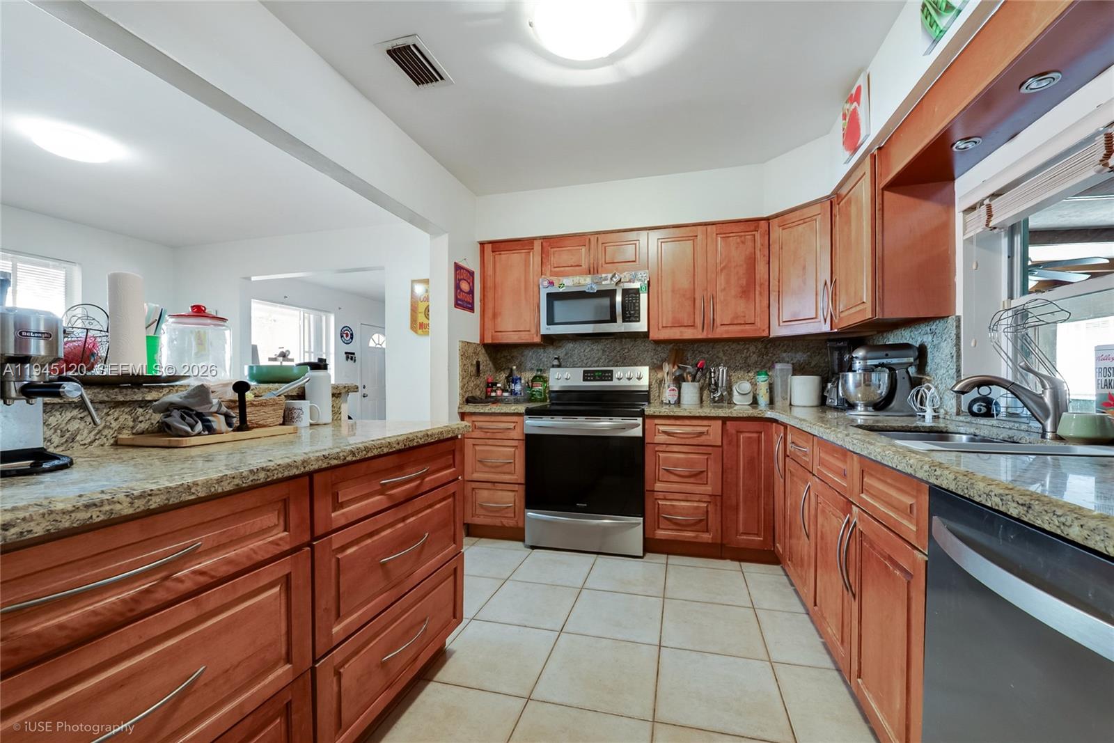 A kitchen features wood cabinets, granite countertops, stainless steel appliances, and tile flooring — 5700 SW 45th Ter, Miami FL 33155, MIAMI, FL