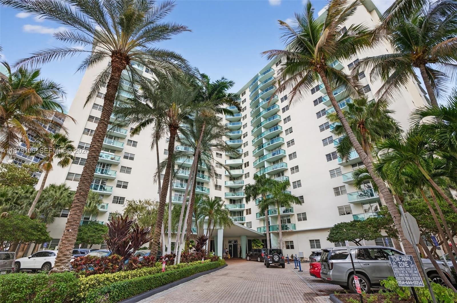 A multi-story residential building with balconies is surrounded by palm trees and a paved driveway — 3801 S Ocean Dr # 4R, Hollywood FL 33019, HOLLYWOOD, FL