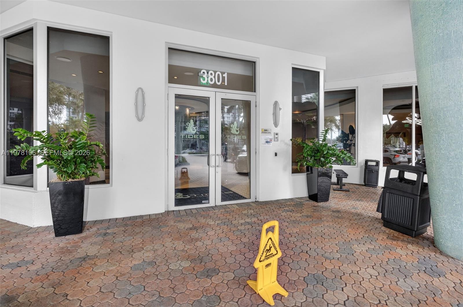 The exterior entrance of a building features glass double doors, potted plants, and pavers — 3801 S Ocean Dr # 4R, Hollywood FL 33019, HOLLYWOOD, FL