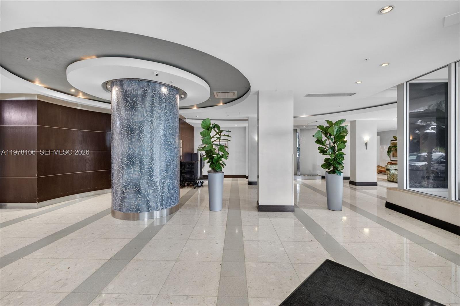 A modern lobby features a blue mosaic-tiled circular column, potted plants, and light-colored tile flooring — 3801 S Ocean Dr # 4R, Hollywood FL 33019, HOLLYWOOD, FL