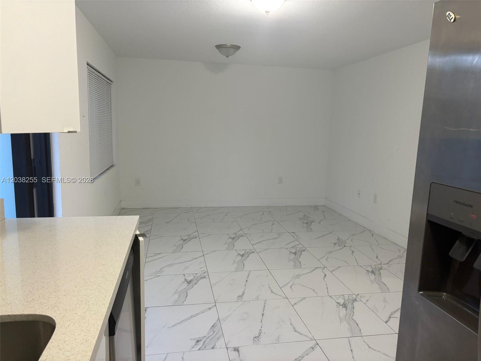 A kitchen area with white walls, marble-patterned tile flooring, and a stainless steel refrigerator — 6280 NW 22nd Ct # 2, Miami FL 33147, MIAMI, FL