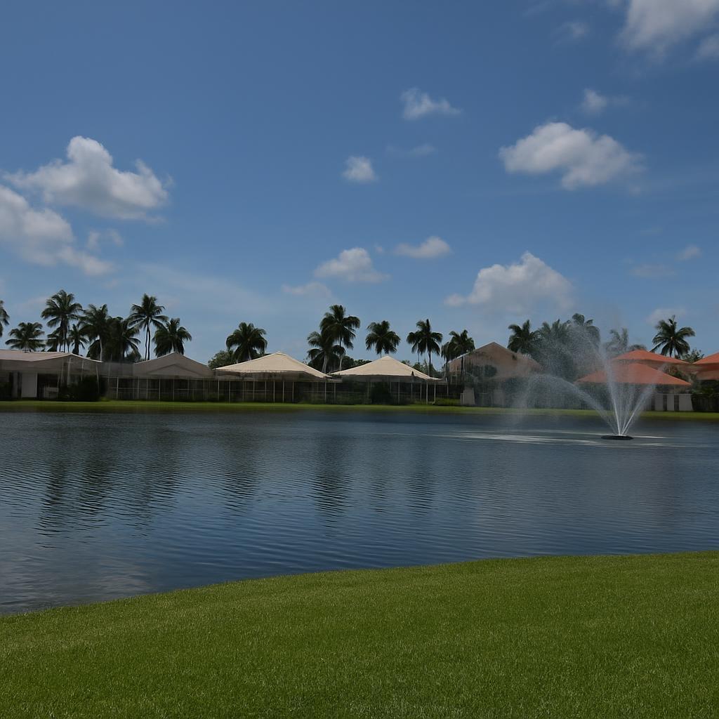 A pond with a fountain sits in front of houses and palm trees under a sky — 5463 NW 41st Terrace, Boca Raton FL 33496, BOCA RATON, FL