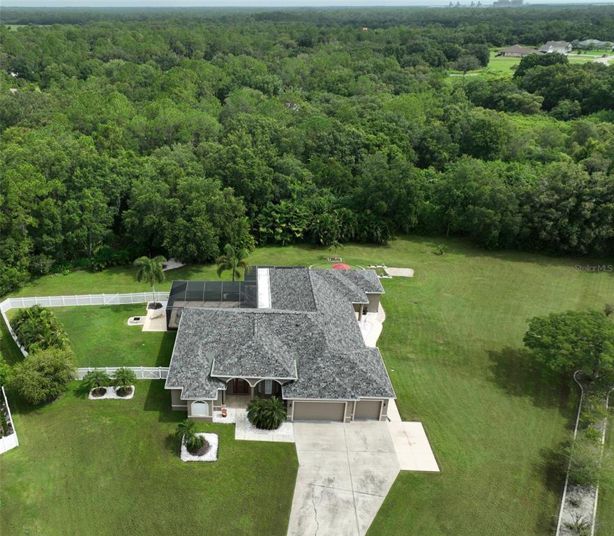 A backyard patio features a putting green, a red umbrella, and a wooden table — 17706 BRIDLEWOOD COURT, PARRISH, FL