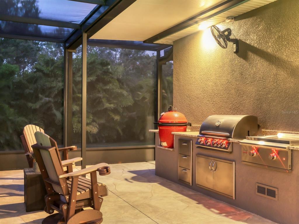 A covered outdoor kitchen and pool area with a hot tub at dusk — 17706 BRIDLEWOOD COURT, PARRISH, FL