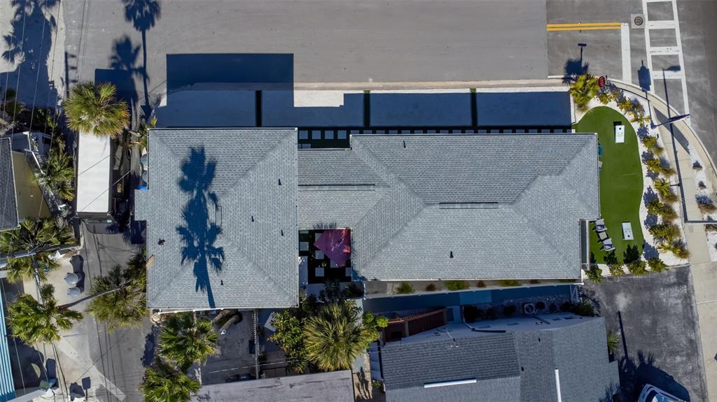 An aerial view shows a house with a gray shingled roof and a putting green — 12620 GULF BOULEVARD, TREASURE ISLAND, FL