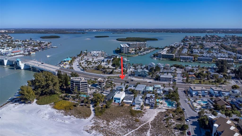 An aerial view shows a coastal neighborhood with a red arrow pointing toward a property — 12620 GULF BOULEVARD, TREASURE ISLAND, FL