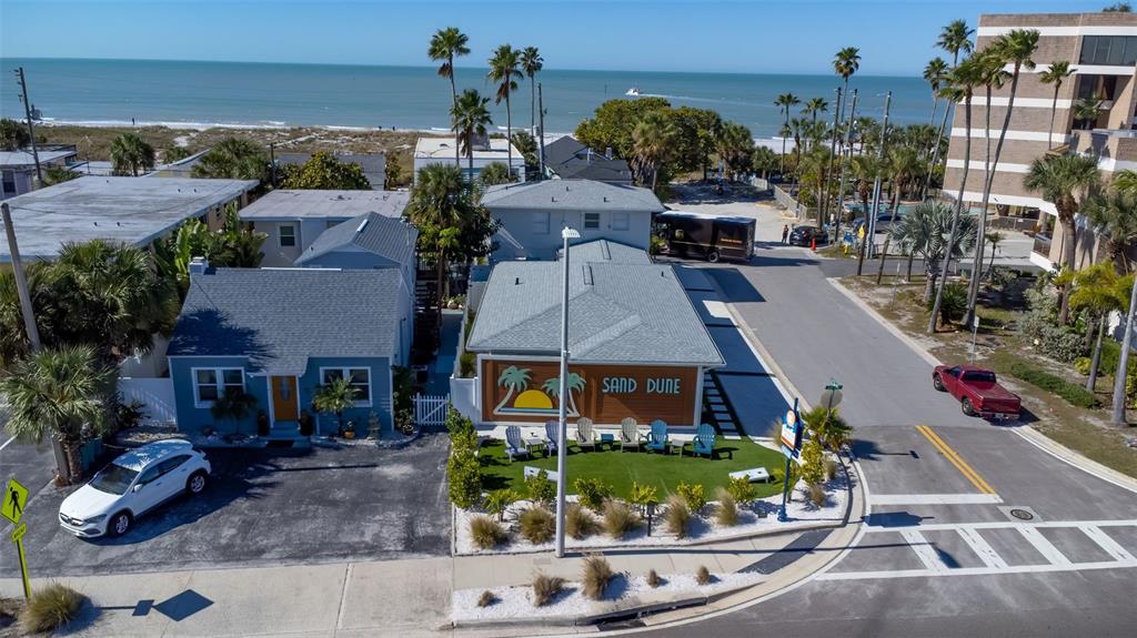An aerial view shows two beach-style houses with a small lawn and nearby ocean — 12620 GULF BOULEVARD, TREASURE ISLAND, FL