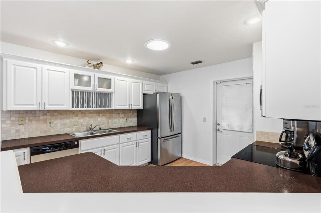A kitchen features white cabinets, dark countertops, stainless steel appliances, and a tiled backsplash — 17695 SE 114TH COURT, SUMMERFIELD, FL