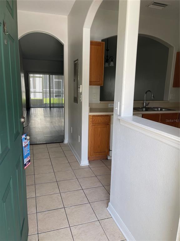An entryway with tile flooring leads to a kitchen with wood cabinets and a living area — 3548 HIGH HAMPTON CIRCLE, TAMPA, FL