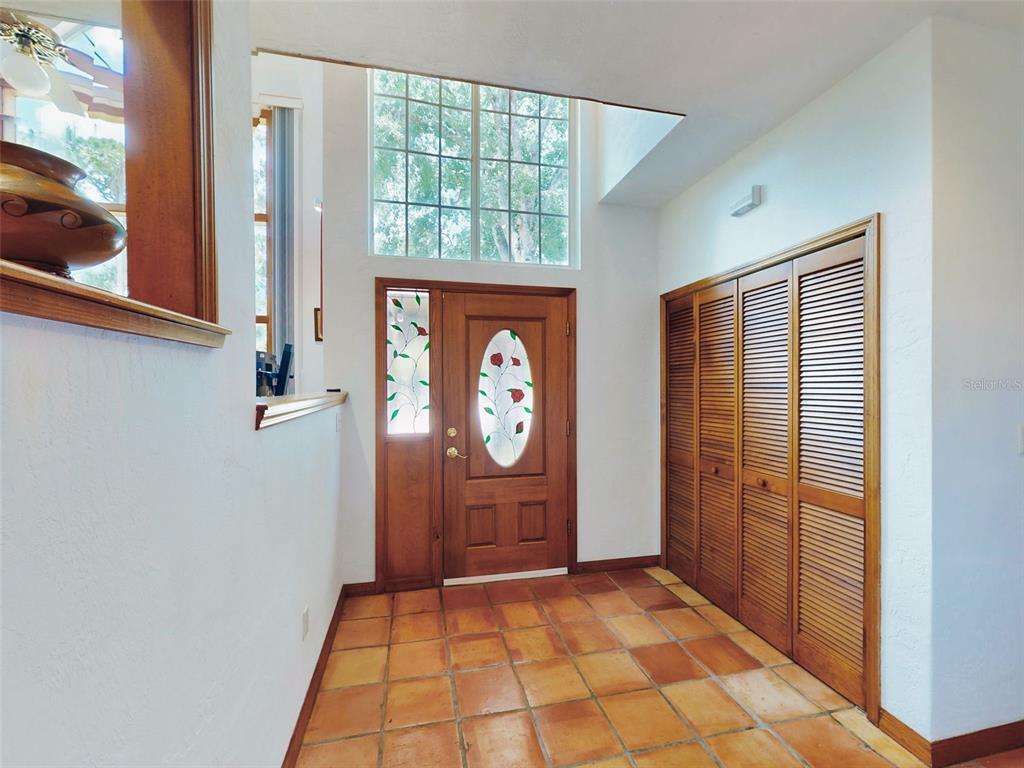 An entryway features a wooden front door with a stained-glass insert and terracotta tile flooring — 1205 WILLIAMS ROAD, NEW SMYRNA BEACH, FL