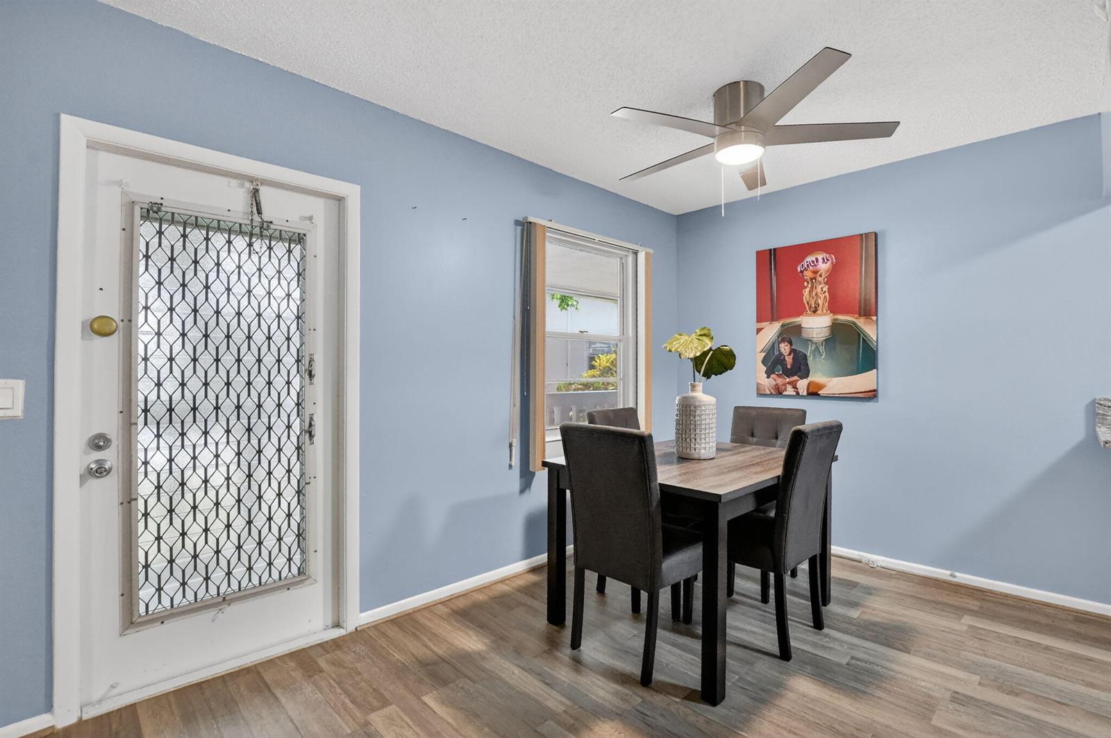 A dining area with light blue walls, wood-look flooring, a ceiling fan, and a table — 262 Ventnor R, Deerfield Beach FL 33442, DEERFIELD BEACH, FL