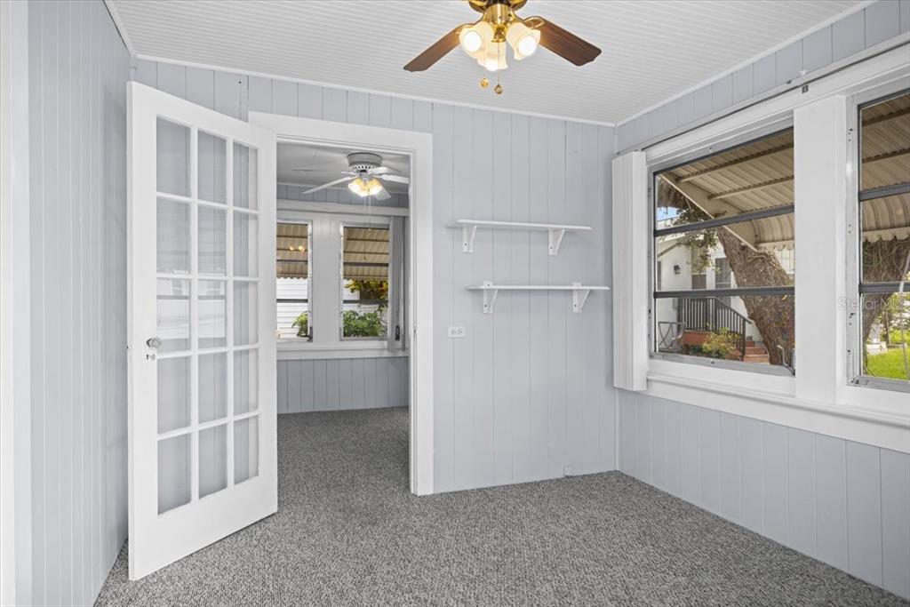 A sunroom with light blue paneled walls, gray carpeting, white shelving, and a ceiling fan — 9 SEMINOLE DRIVE, BRADENTON, FL