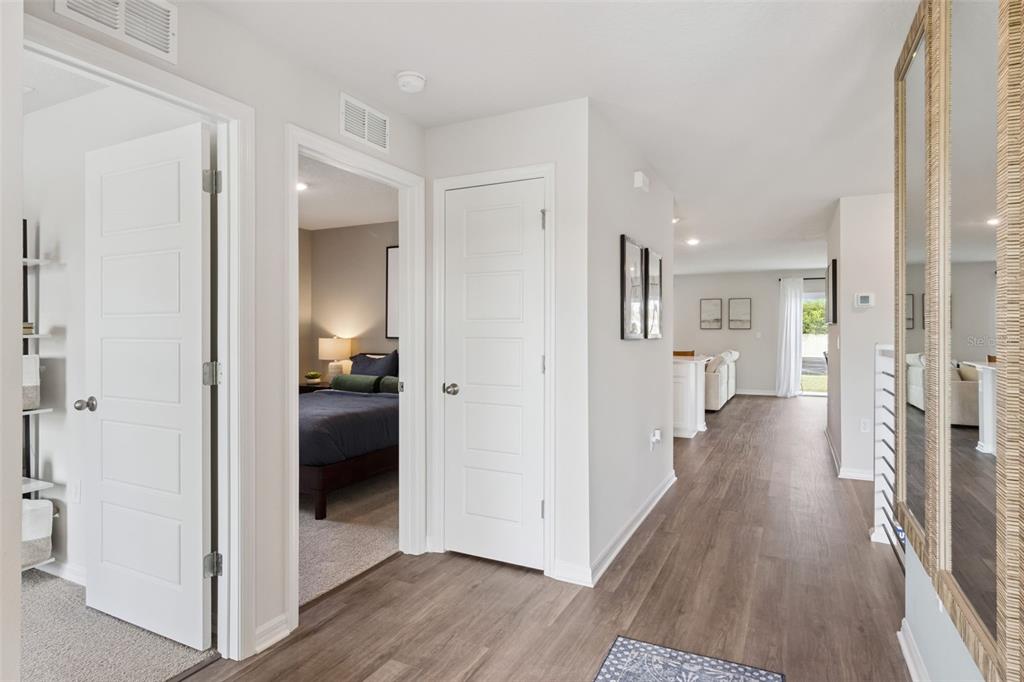 A hallway with light-colored walls and wood-look flooring leads toward an open-concept living area — 2799 ADELINE AVENUE, WINTER HAVEN, FL