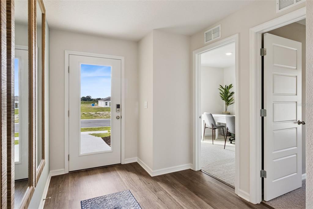 An entryway with wood-look flooring, a glass-paneled front door, and a doorway leading to an office — 2799 ADELINE AVENUE, WINTER HAVEN, FL