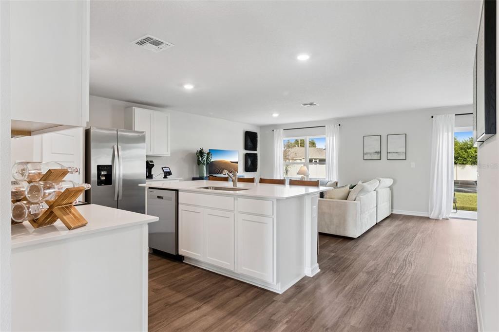A modern open-concept kitchen with white cabinets and a center island overlooks a living area — 2799 ADELINE AVENUE, WINTER HAVEN, FL