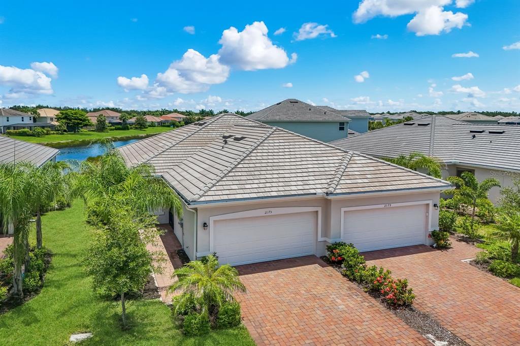 An aerial view of a duplex home with a tiled roof and brick driveway — 2175 DRAGONFRUIT WAY, NAPLES, FL