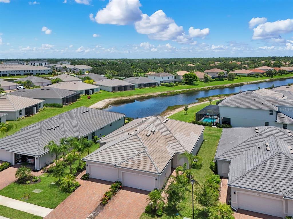 An aerial view shows several suburban houses with tiled roofs and a canal nearby — 2175 DRAGONFRUIT WAY, NAPLES, FL