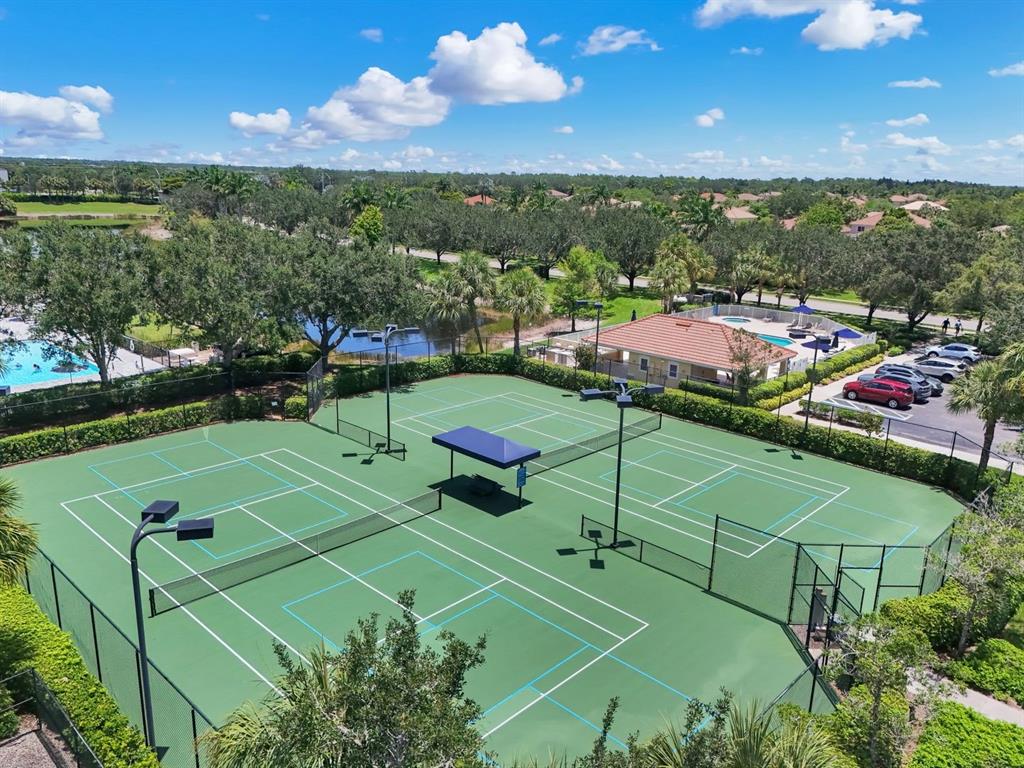 An aerial view of two outdoor tennis courts surrounded by landscaping and a parking lot — 2175 DRAGONFRUIT WAY, NAPLES, FL