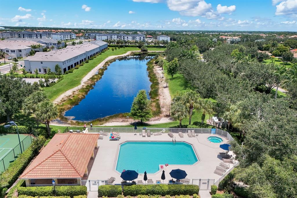 An aerial view shows a swimming pool, hot tub, and clubhouse beside a long pond — 2175 DRAGONFRUIT WAY, NAPLES, FL