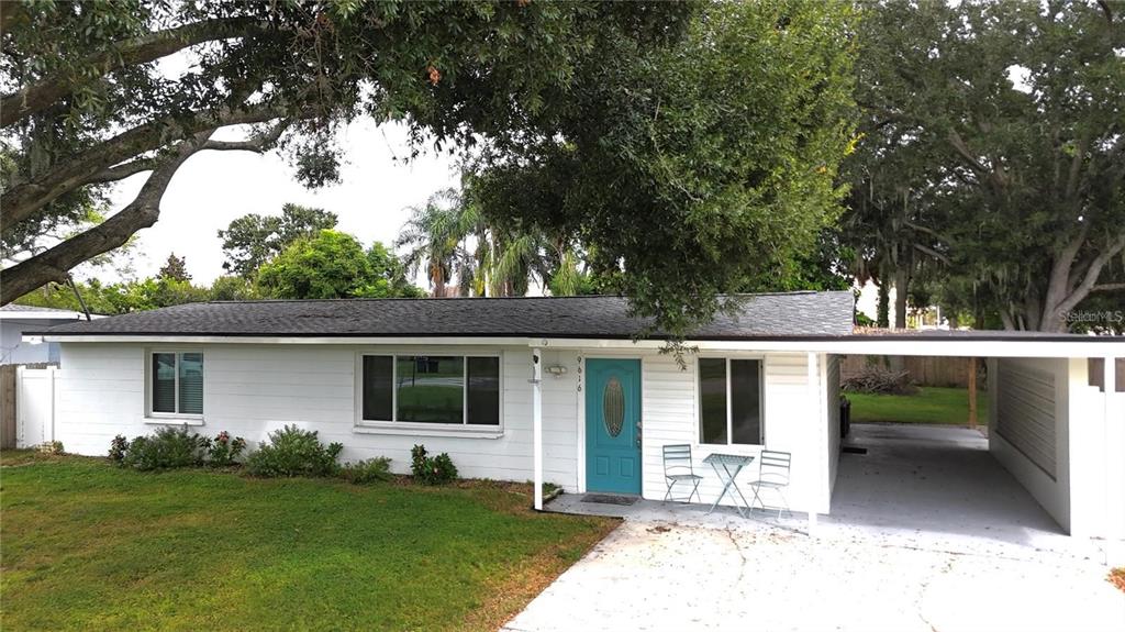 A single-story white house with a teal front door and an attached carport — 9616 PINE RIDGE AVENUE, RIVERVIEW, FL