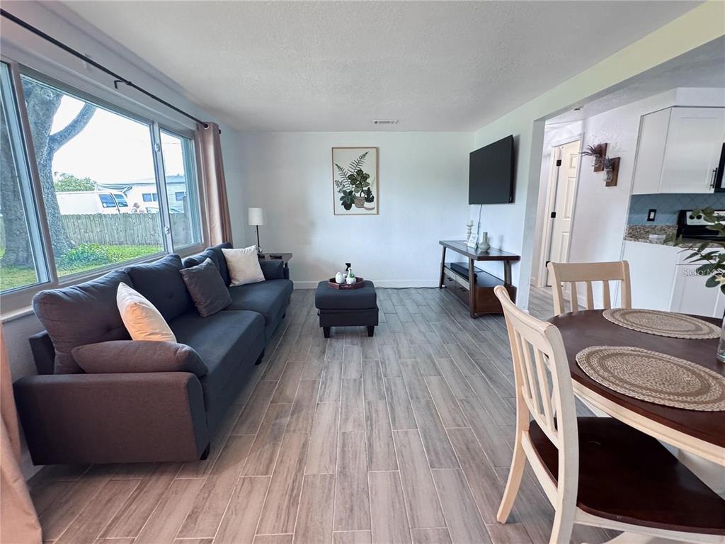 A living room features gray tile flooring, a dark sofa, and an adjacent dining area — 9616 PINE RIDGE AVENUE, RIVERVIEW, FL