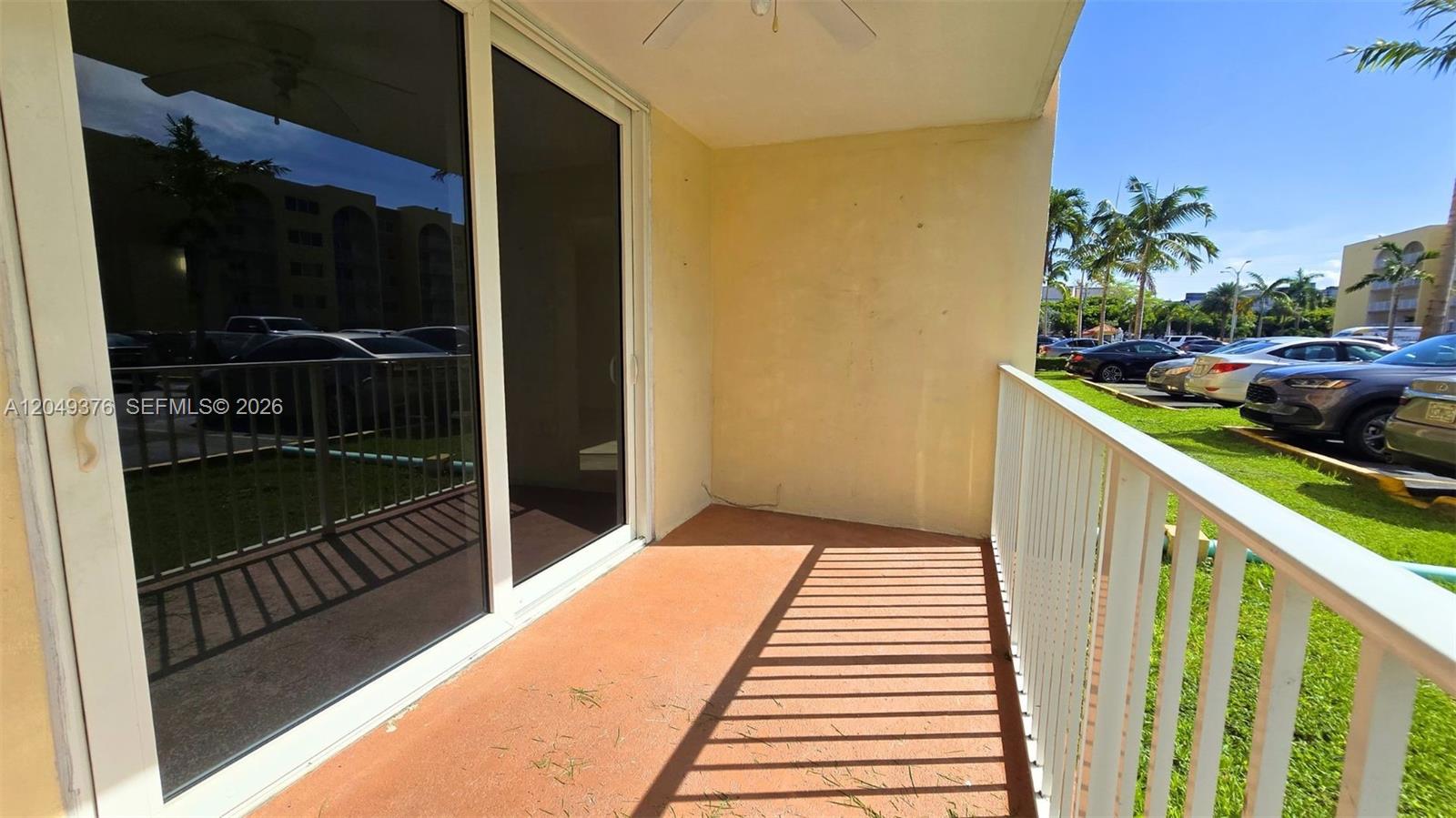 A ground-floor balcony features a sliding glass door, orange flooring, and a white railing — HIALEAH, FL