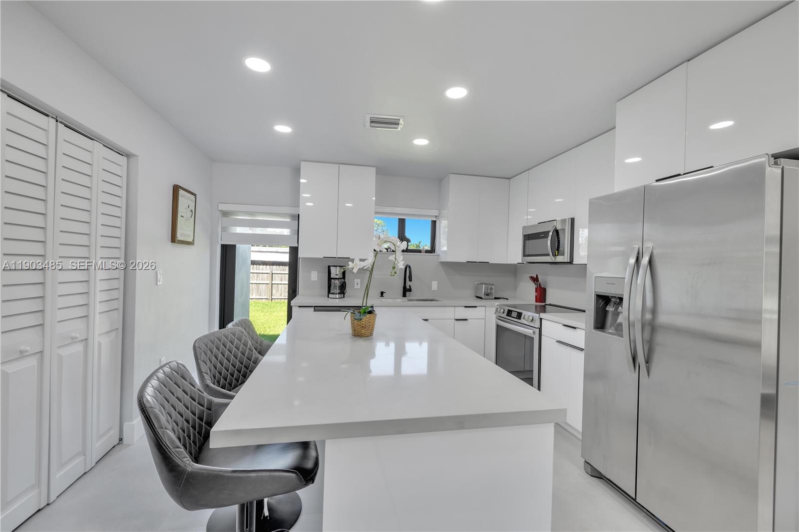 A modern kitchen features white cabinets, a large quartz island, and stainless steel appliances — 6021 SW 19th St, Miami FL 33155, MIAMI, FL