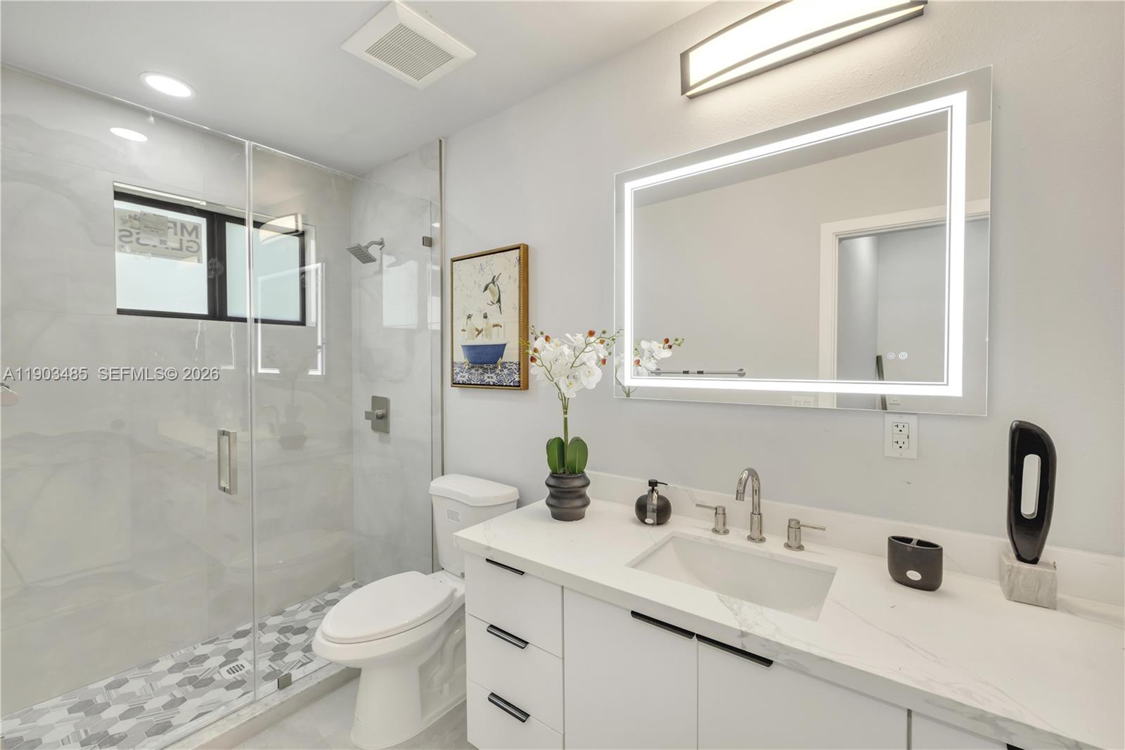 This modern bathroom features a glass-enclosed shower, a white vanity, and a backlit mirror — 6021 SW 19th St, Miami FL 33155, MIAMI, FL