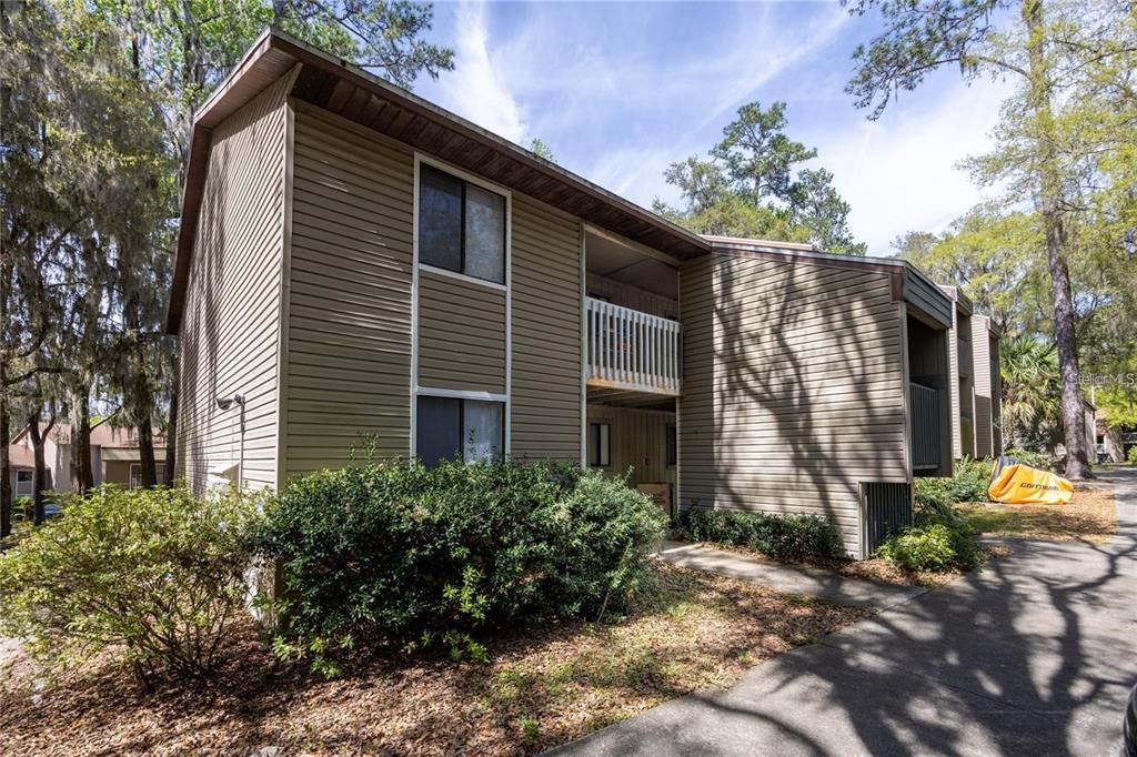 Exterior view of a two-story apartment building with tan siding and a balcony — 127 SE 16TH AVENUE UNIT S-105, GAINESVILLE, FL