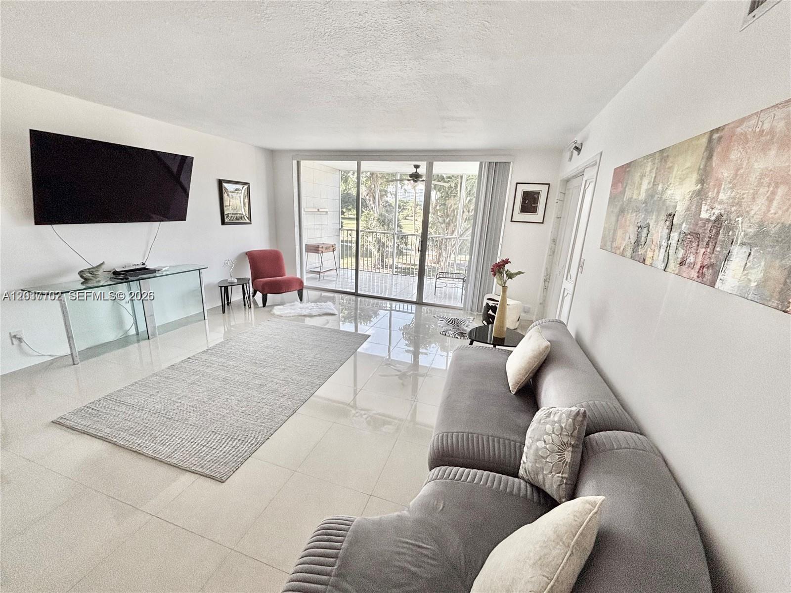 A living room features a gray sofa, a glass console table, and a balcony view — 3051 S Palm Aire Dr # 201, Pompano Beach FL 33069, POMPANO BEACH, FL