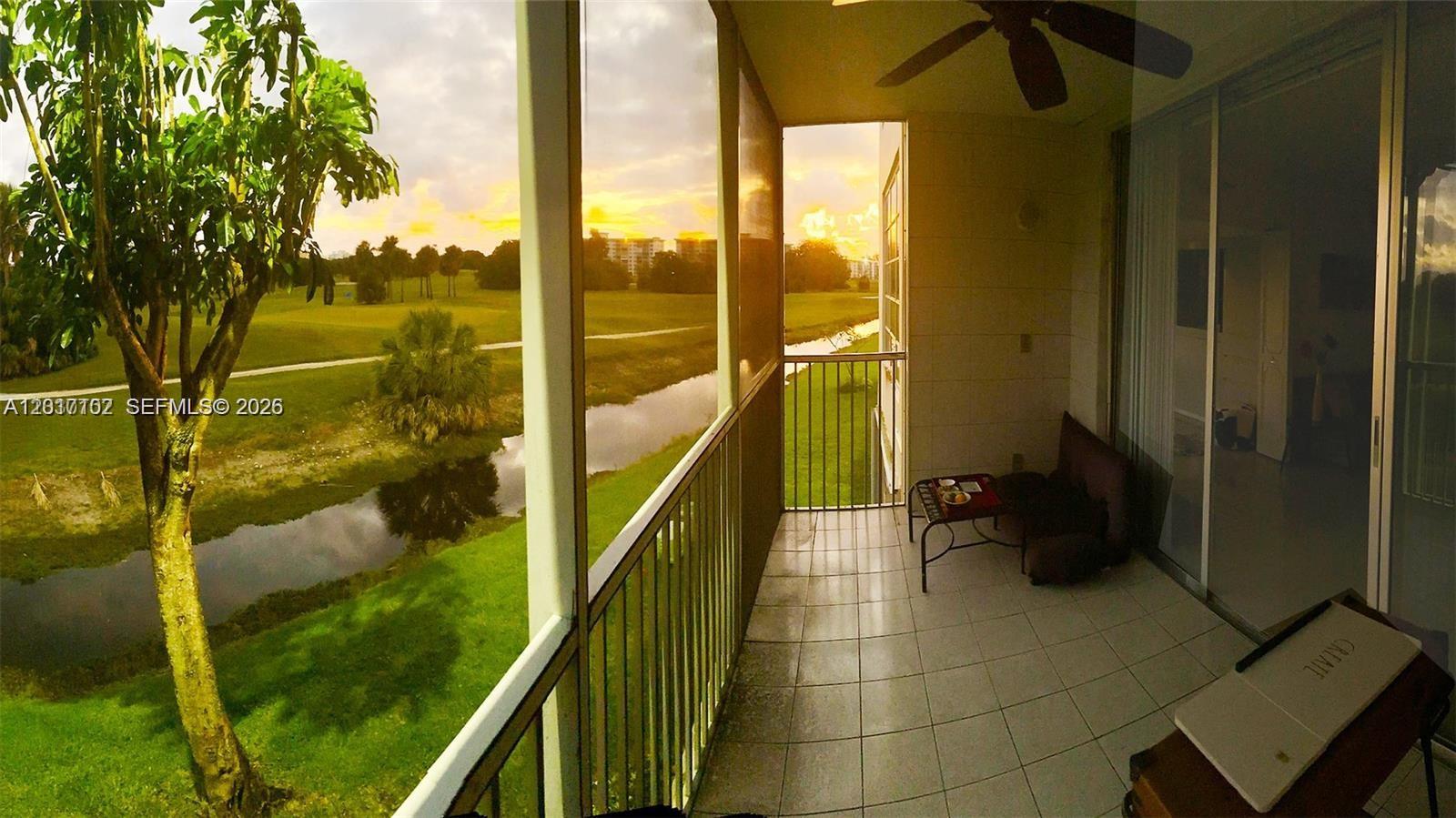 A screened balcony overlooks a golf course with a small canal and sunset sky — 3051 S Palm Aire Dr # 201, Pompano Beach FL 33069, POMPANO BEACH, FL