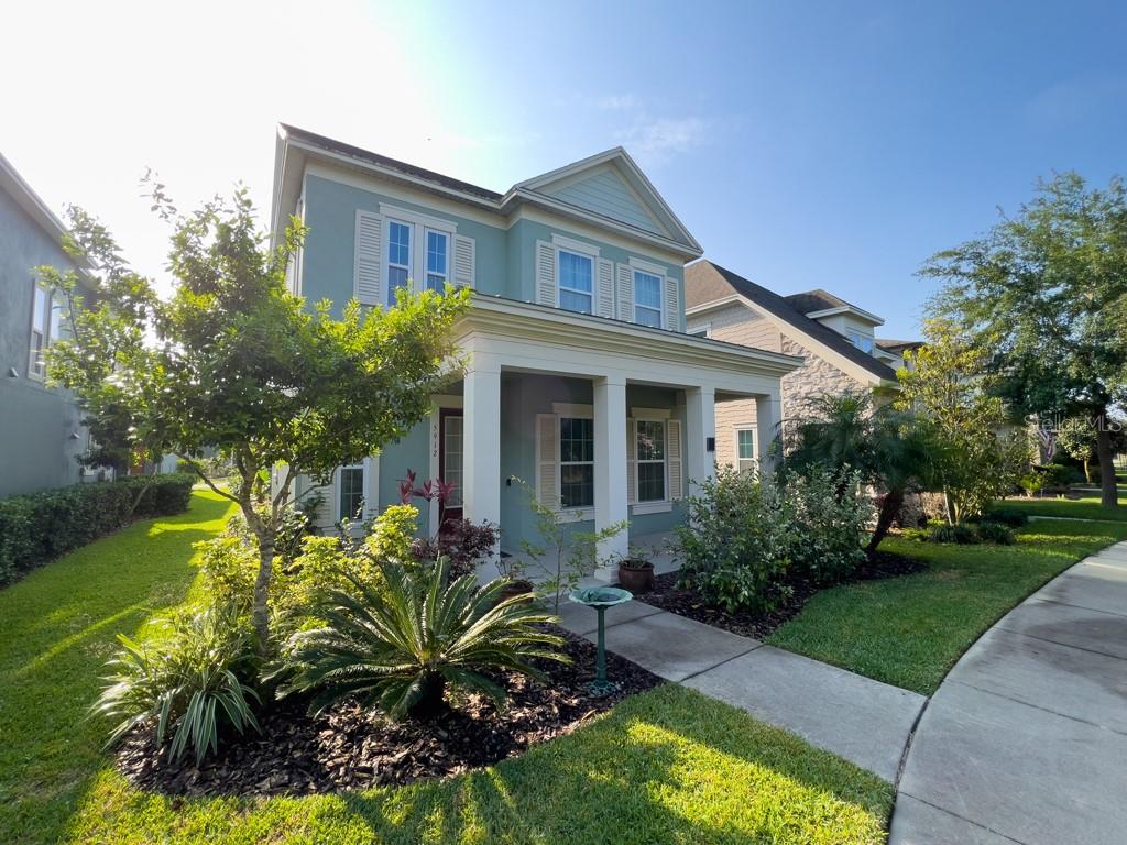 A two-story light green house with a front porch and a landscaped yard — 5912 VILLAGE CENTER DRIVE, LITHIA, FL