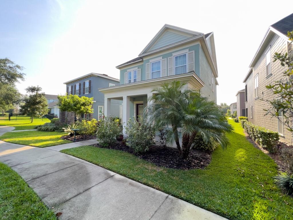 A two-story light green house with a front porch and a palm tree in front — 5912 VILLAGE CENTER DRIVE, LITHIA, FL