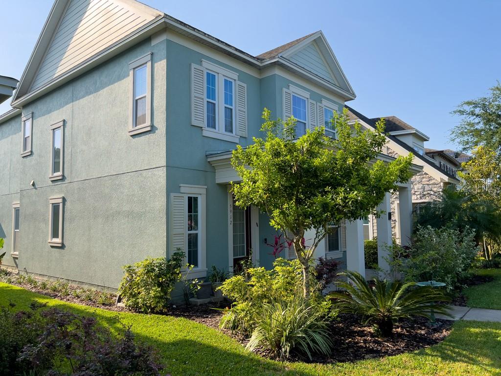 A two-story light green house with a front porch, landscaping, and white window shutters — 5912 VILLAGE CENTER DRIVE, LITHIA, FL