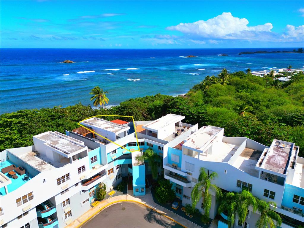 An aerial view shows a multi-story coastal apartment complex with flat roofs and ocean views — St 686 COND. CHALETS DE LA PLAYA UNIT 579, VEGA BAJA, PR