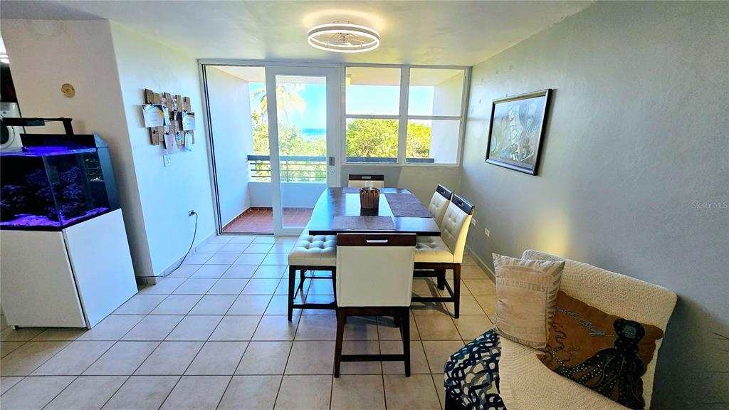 A dining area with a table, chairs, a fish tank, and a balcony with ocean views — St 686 COND. CHALETS DE LA PLAYA UNIT 579, VEGA BAJA, PR