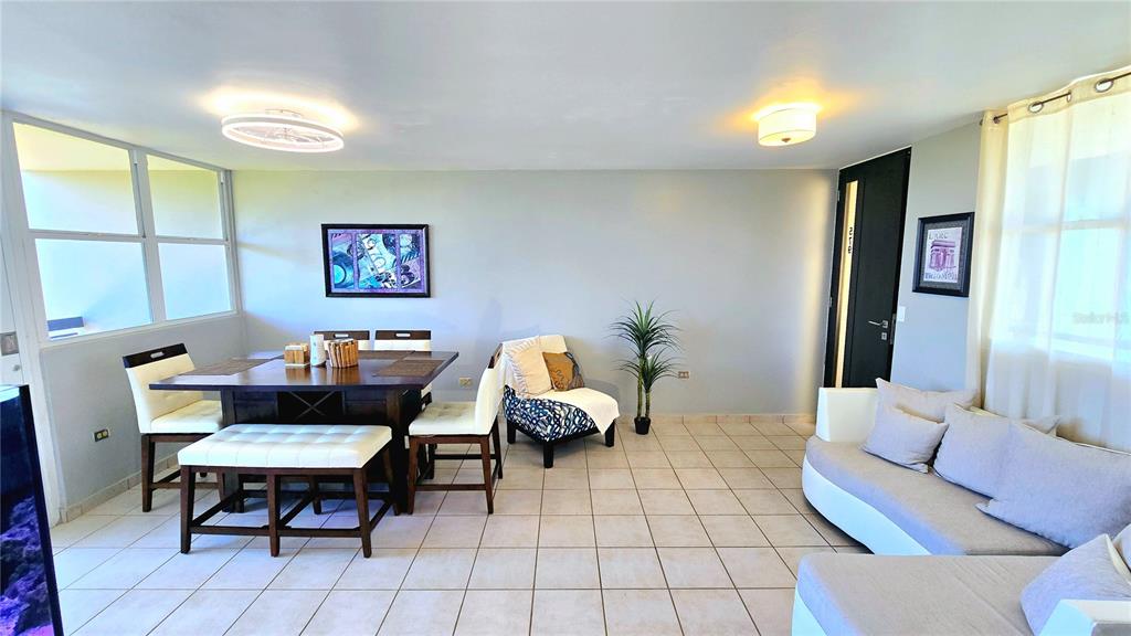 A dining area and living room with tile floors, a dark wood table, and sofa — St 686 COND. CHALETS DE LA PLAYA UNIT 579, VEGA BAJA, PR